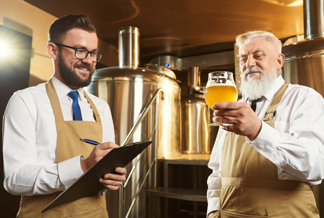 Two  brewery workers examining a glass of beer