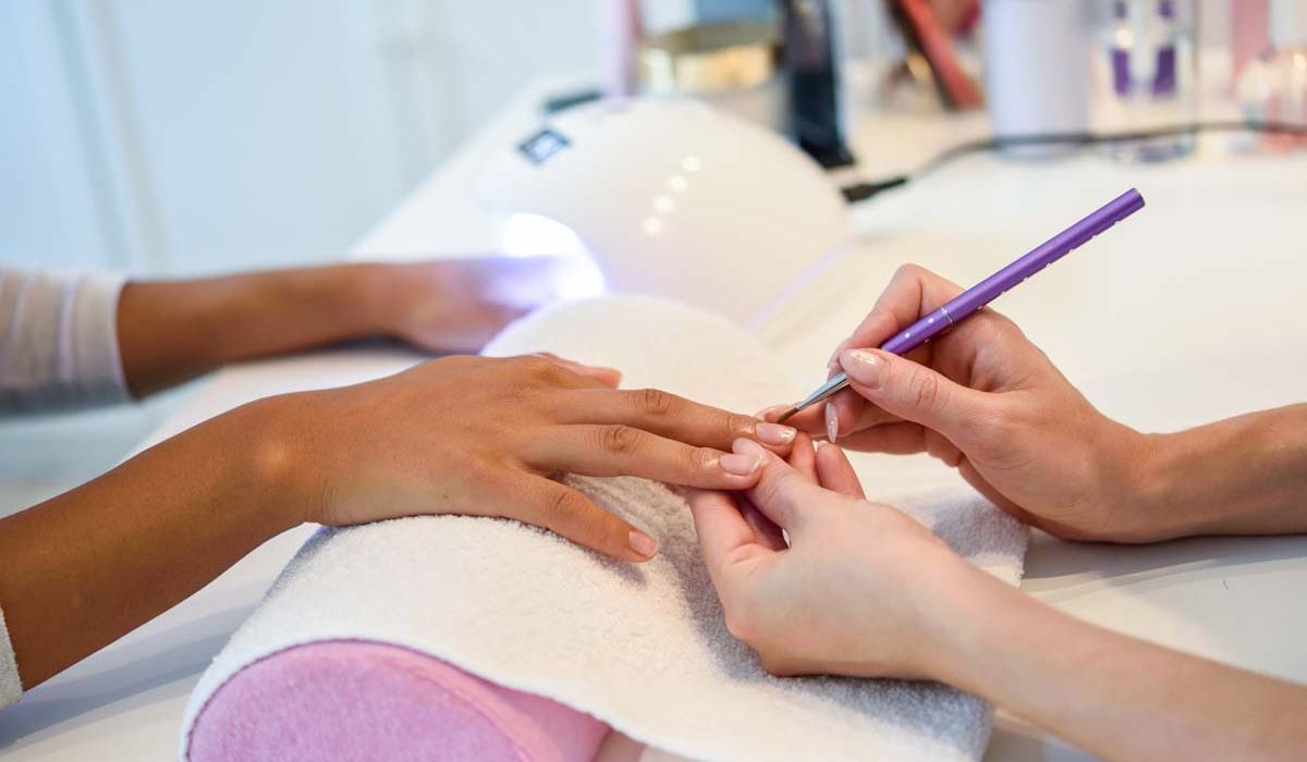A woman wearing blue glasses and a red glove is having her teeth cleaned at a dental office.