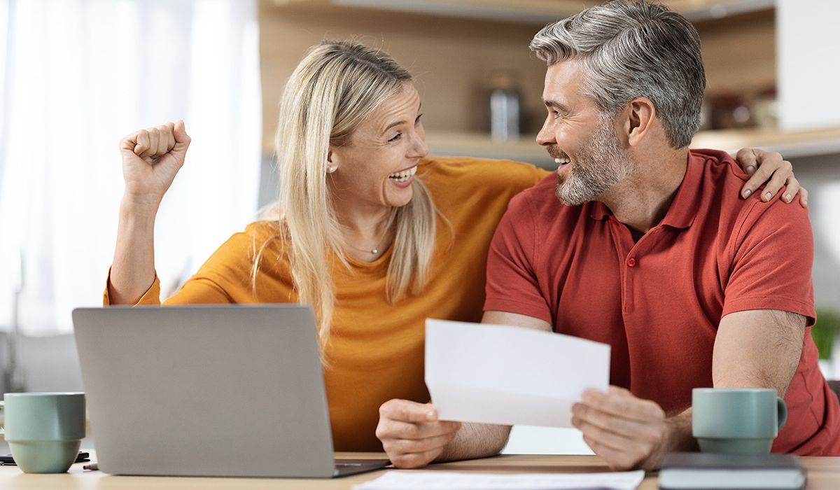 Photo of happy emotional spouses reading a letter in the kitchen