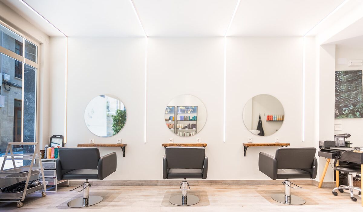 Modern bright beauty salon interior with black chairs and round mirrors